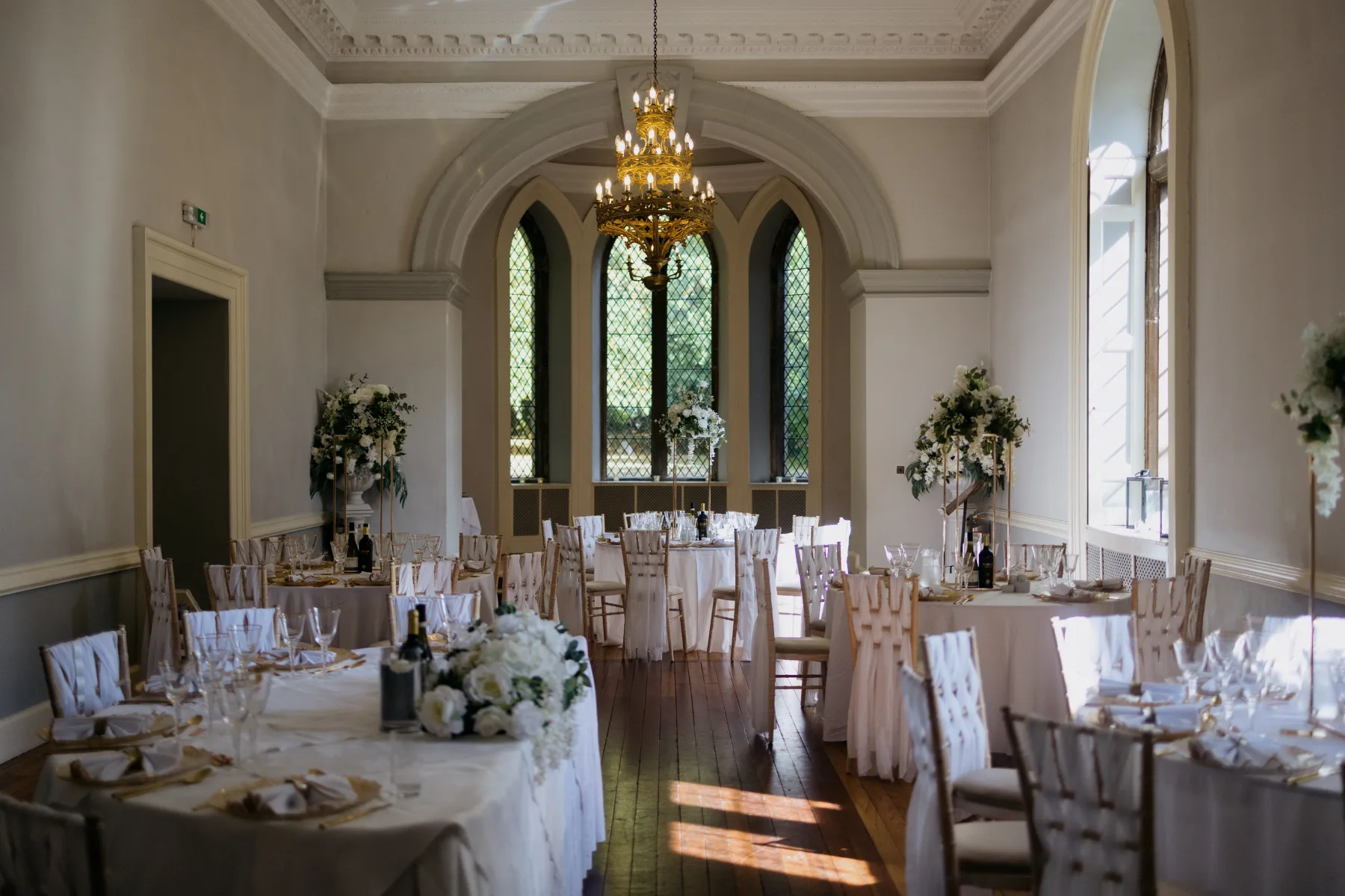 Elegant wedding breakfast room beneath chandeliers at Clearwell Castle