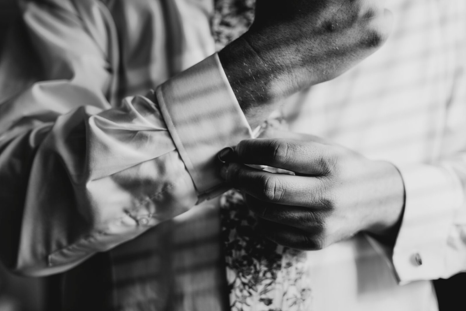 Groom fastening cufflinks in black and white