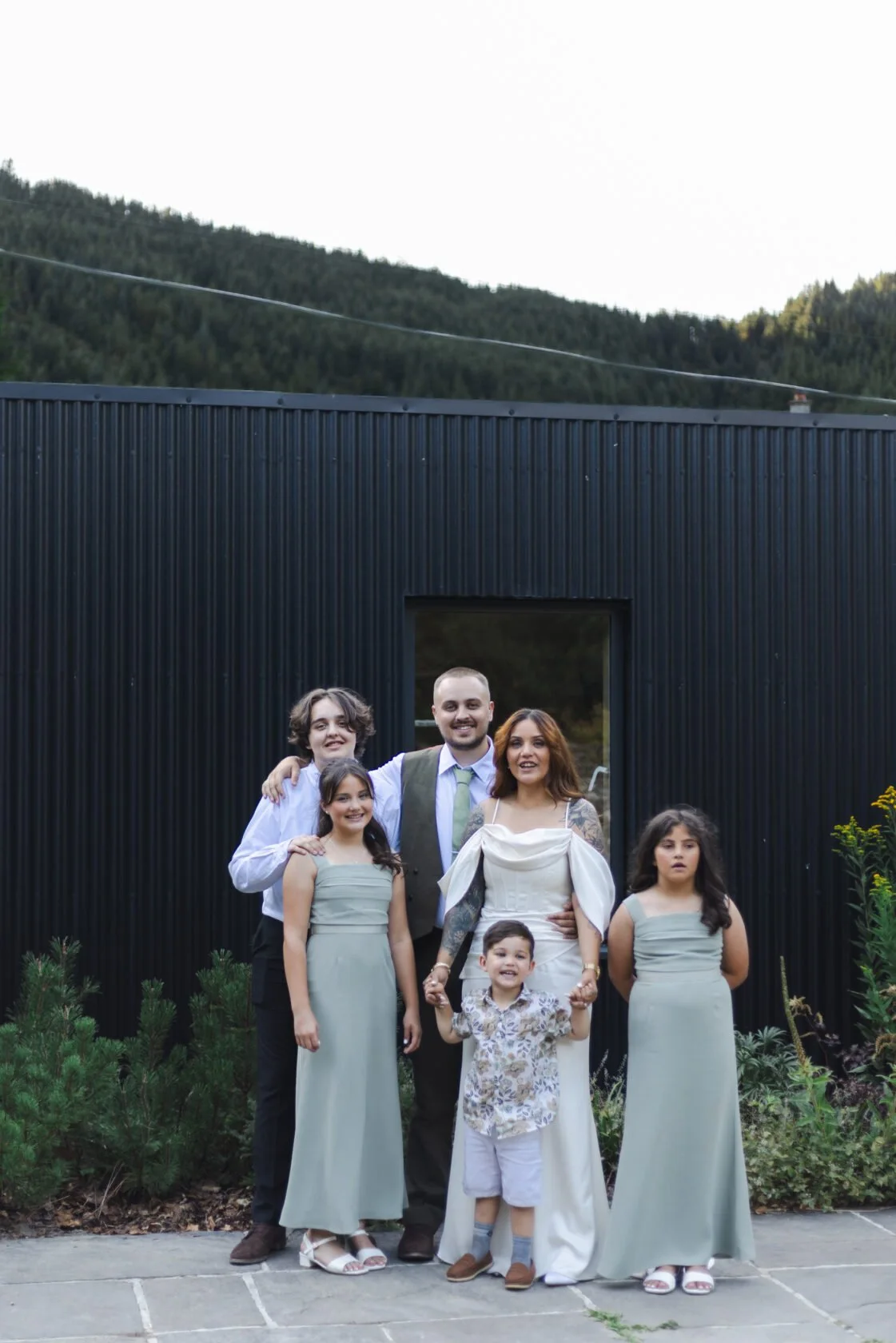 Family group posing outside a modern black wedding venue