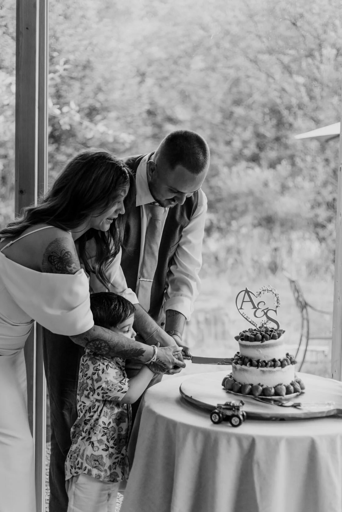 A couple and child cutting their wedding cake together