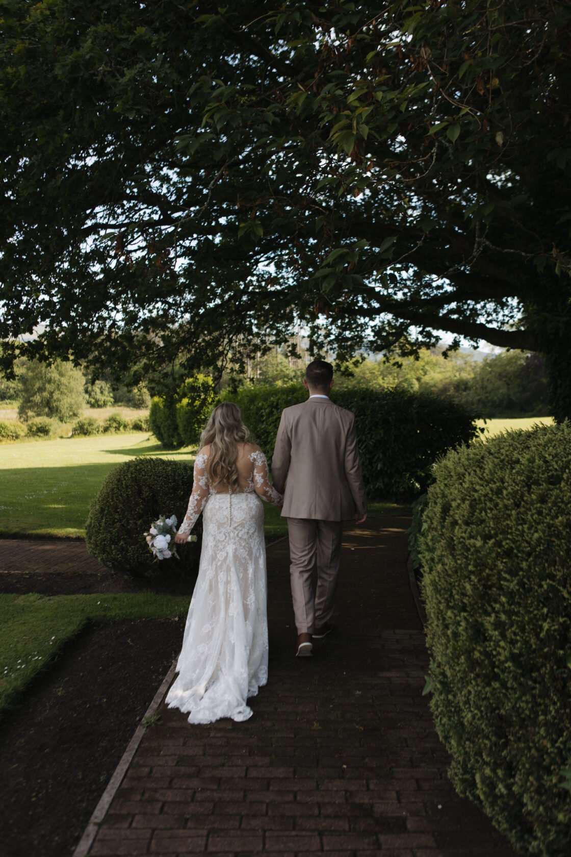 Newlyweds walking hand in hand along a garden path