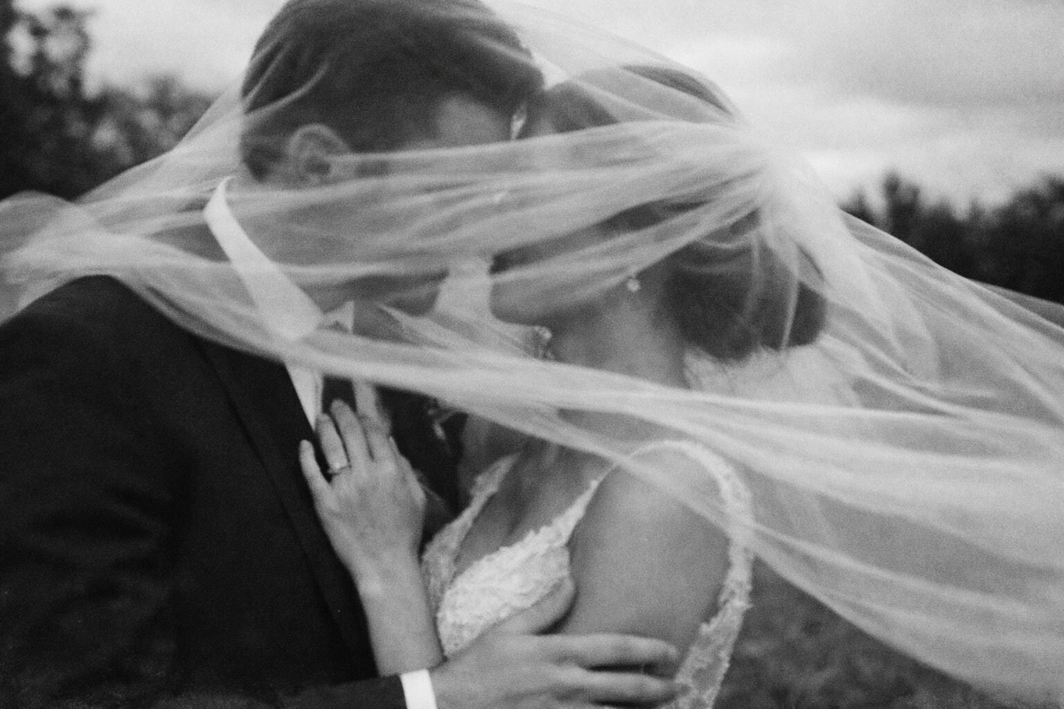 Newlyweds sharing a quiet moment beneath the veil in black and white