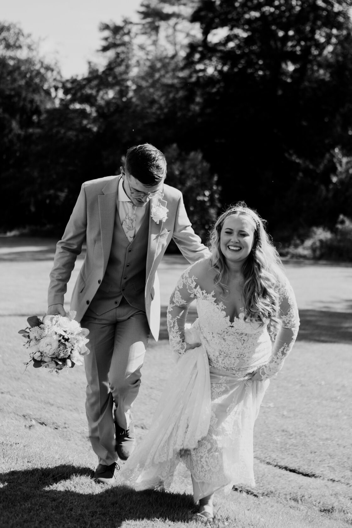Newlyweds laughing as they walk together, in black and white